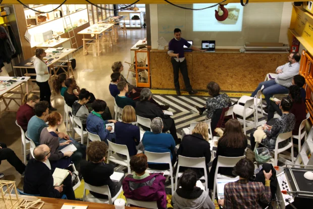 a view from above of 25 people sat round looking at a presentation and having a discussion.