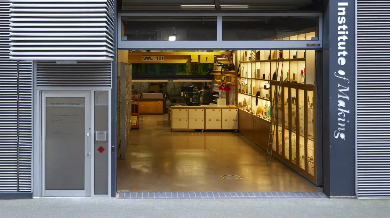 An exterior view of a building with large front doors opened up to reveal the interior Materilas Library and workshop. On the right hand side of the door frame a log reads "Institute of Making"