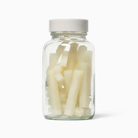 Glass jar full of cream coloured rods of plastic