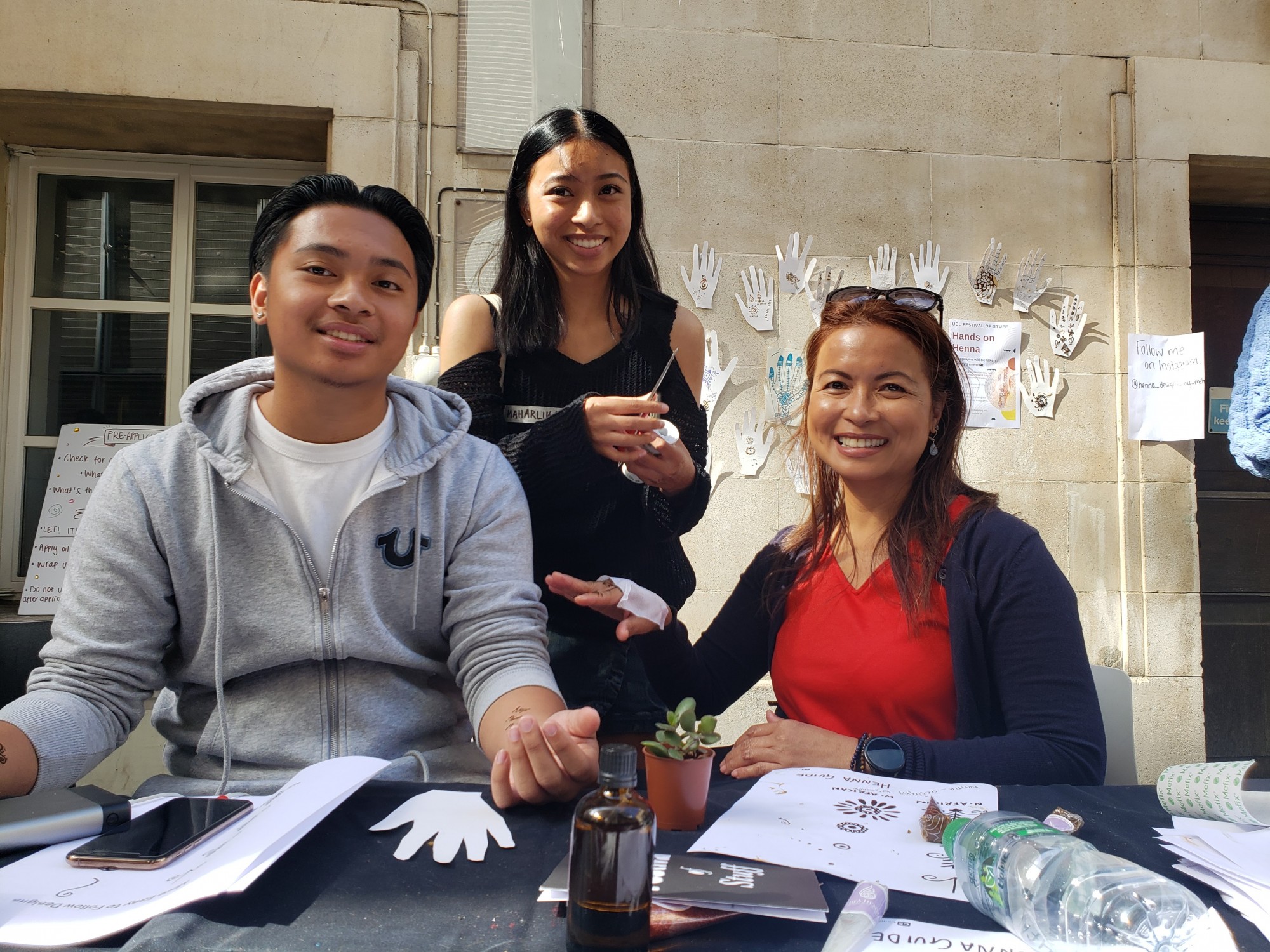 A participant teaching their family henna skills at the Festival of Stuff